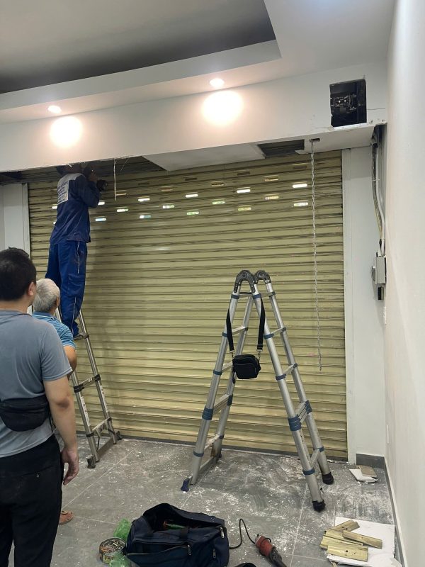 Thợ sửa cửa cuốn làm việc tại ô kỹ thuật phía trên cửa