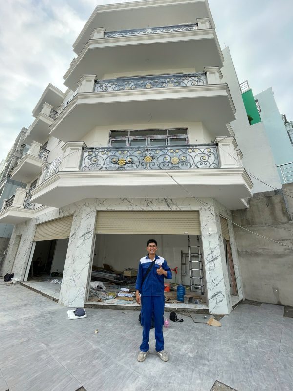Sửa cửa cuốn: kỹ thuật viên trước công trình có cửa cuốn mặt tiền